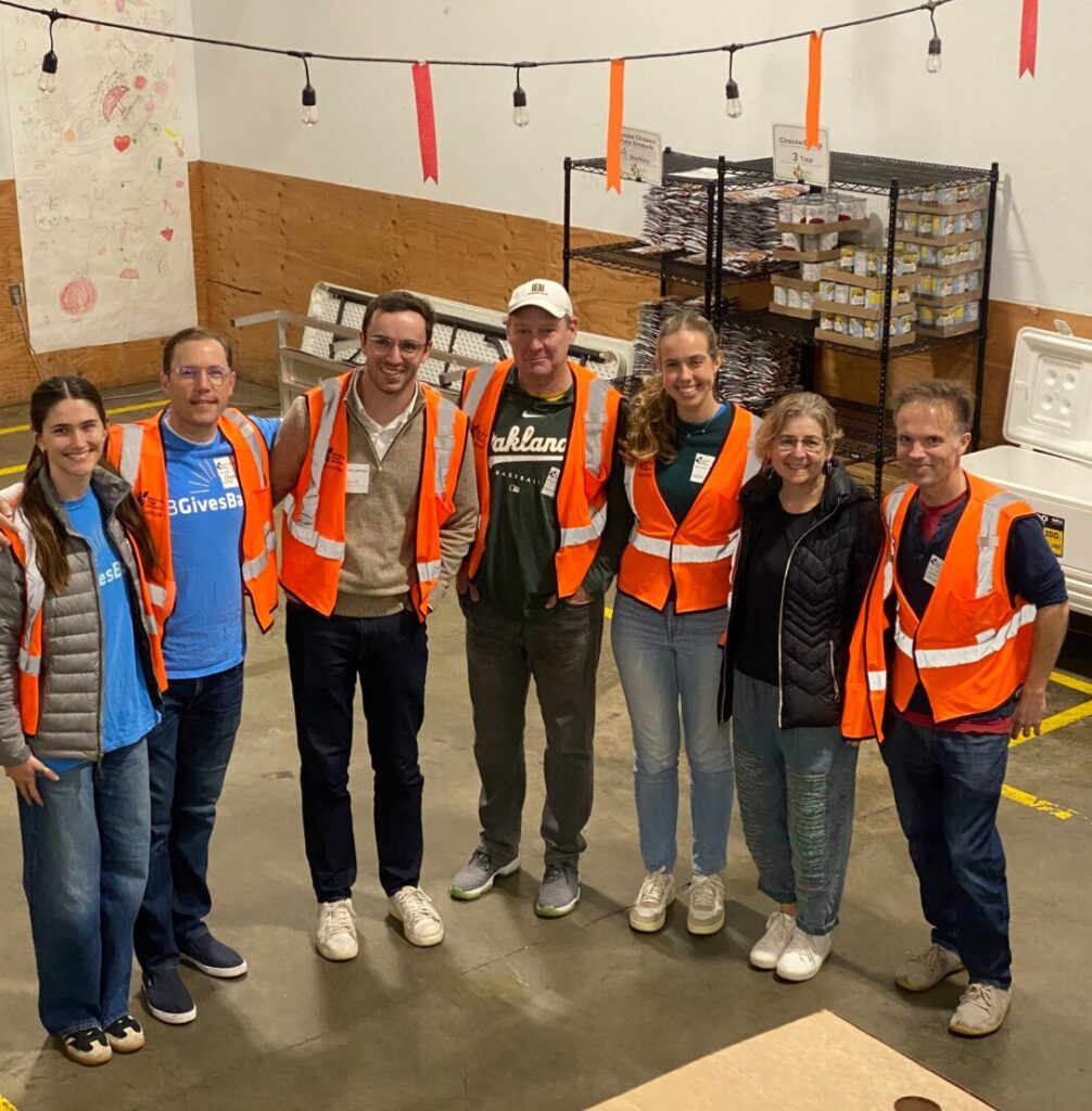 A group of volunteers in safety vests posing together in the Berkeley Food Network warehouse